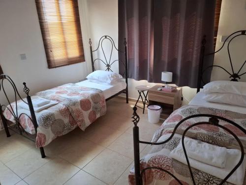 a bedroom with two beds and a table and a window at Sunset Green 01 in Paphos City