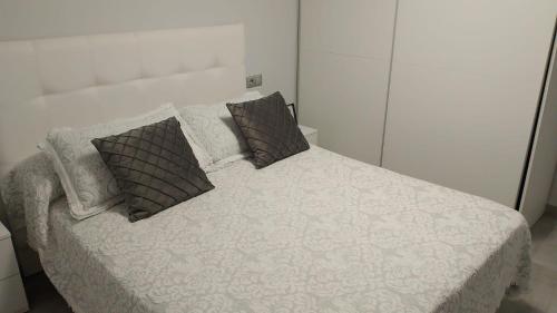 a white bed with three pillows on top of it at Casa Marcé in Córdoba