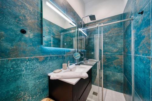 une salle de bain carrelée bleue avec un lavabo et une douche dans l'établissement La grande estacade 2, à Grenoble