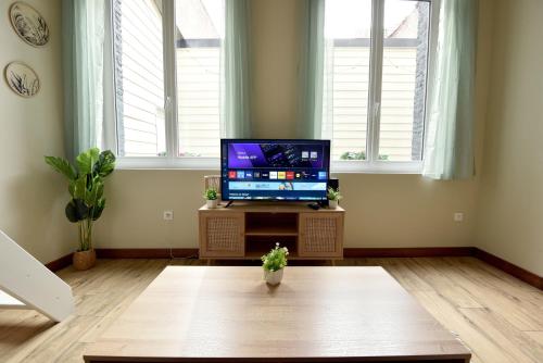 a living room with a tv and a table at Le Bleu OMER - Jacuzzi & Netflix - Terrasse privée I Coeur de ville & Transports - Idéal FAMILLE - OFFRE SPÉCIALE in Saint-Omer