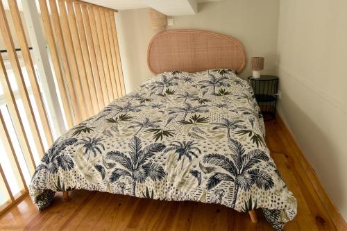 a bedroom with a bed with a blanket with palm trees at Le Bleu OMER - Jacuzzi & Netflix - Terrasse privée I Coeur de ville & Transports - Idéal FAMILLE - OFFRE SPÉCIALE in Saint-Omer