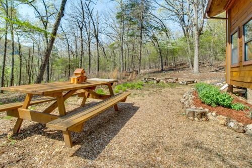 a wooden picnic table with a tea kettle on top at Walk to White River Cotter Cabin with Fire Pit! in Cotter