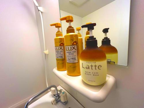a bathroom with four bottles of soap and a mirror at MM Stay Takamatsu Kawaramachi in Takamatsu