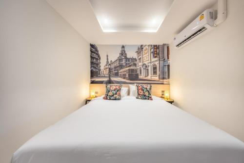 a bedroom with a white bed and a painting on the wall at U TOR Yaowarat in Bangkok