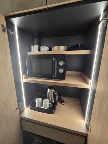 a cupboard with a microwave and a coffee maker in it at MONARC Boutique ApartHotel - SELF CHECK-IN in Iaşi