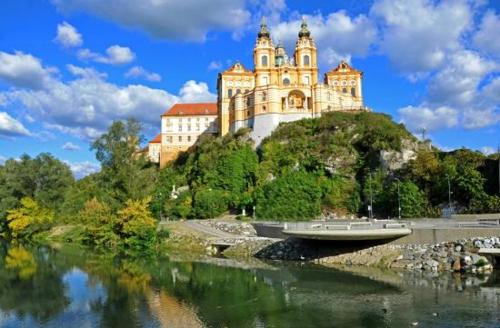 a castle on top of a hill next to a river at Altstadthaus Marille mit Innenhofterrasse in Melk