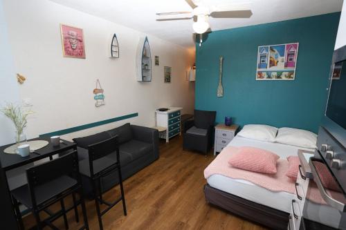 Cette petite chambre comprend un lit, une table et un canapé. dans l'établissement Studio au centre de St Cyp plage, à Saint-Cyprien