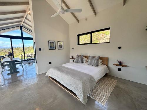 a bedroom with a bed with a ceiling fan at Hillandale Huddle - modern forest cabin near Plett in Plettenberg Bay