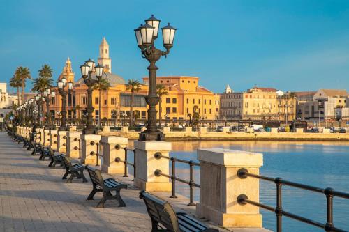 a row of benches and street lights next to a body of water at Mövenpick Hotel Bari in Bari