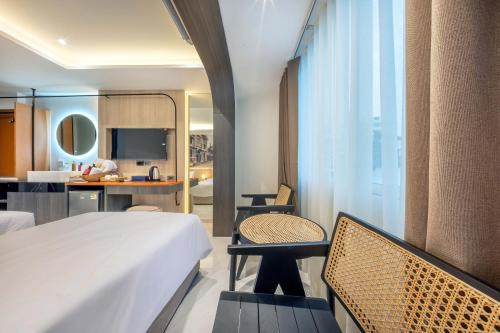 a hotel room with a bed and chairs and a kitchen at U TOR Yaowarat in Bangkok