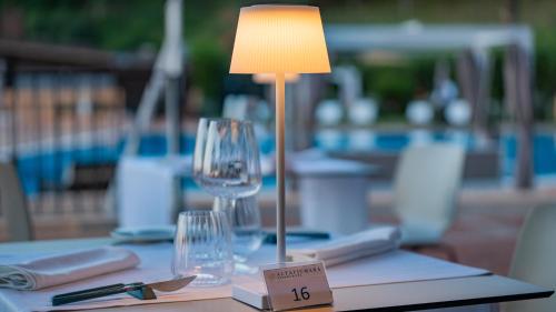 a lamp sitting on a table with glasses on it at Altafiumara Resort & Spa in Villa San Giovanni