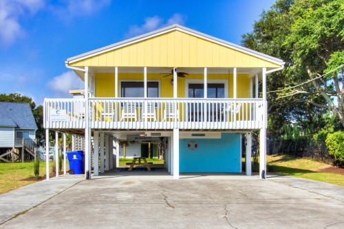 a yellow house with a deck and a picnic table at Sea La Vie by Carolina Beach Realty in Carolina Beach