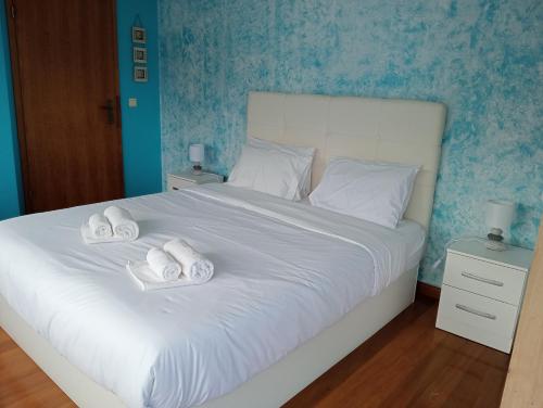 a bedroom with a white bed with towels on it at Surf & Guest Lorena´s House in Ribeira Grande