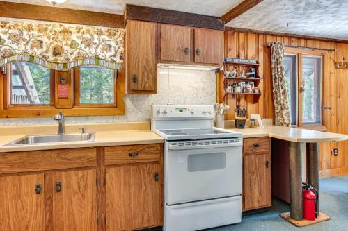 a kitchen with wooden cabinets and a white stove top oven at 2 Mi to Ossipee Lake Forest-View Sanctuary! in Freedom