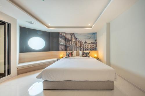 a bedroom with a large bed and a painting on the wall at U TOR Yaowarat in Bangkok