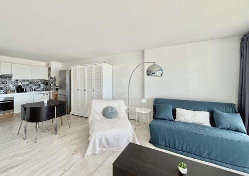 un salon avec un canapé bleu et une cuisine dans l'établissement Côté Mer, à Le Touquet-Paris-Plage