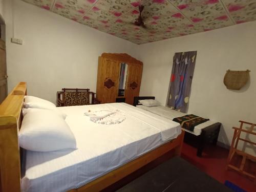 a bedroom with a bed with white sheets and a ceiling at Surf Dream Villa Arugambay in Arugam Bay