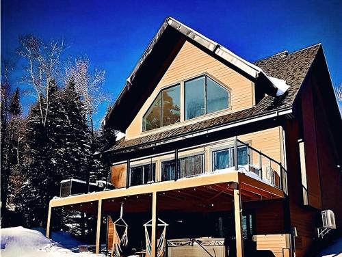 a large house with snow on the ground at Forest Chalet with Hot Tub & Lake Views near Mont Saint-Sauveur in Sainte-Marguerite