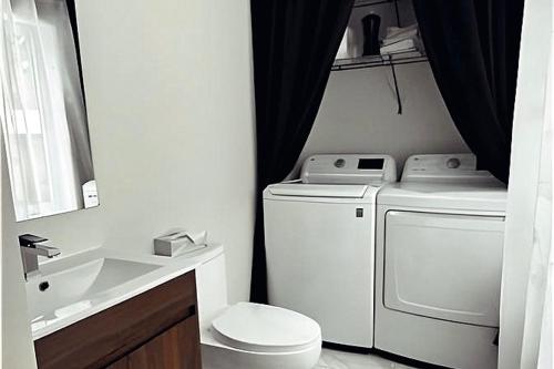 a bathroom with a washing machine and a sink at Forest Chalet with Hot Tub & Lake Views near Mont Saint-Sauveur in Sainte-Marguerite