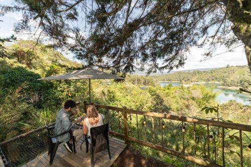 a man and woman sitting at a table under an umbrella at Levit Glamping - Hotel Guatapé Peñol in Guatapé