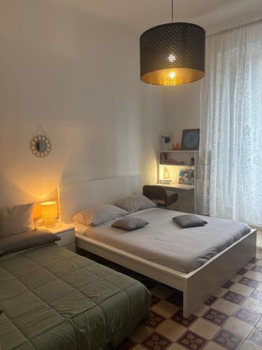 Un dormitorio con dos camas y una lámpara y una ventana. en Da Luis 5 Terre, en La Spezia