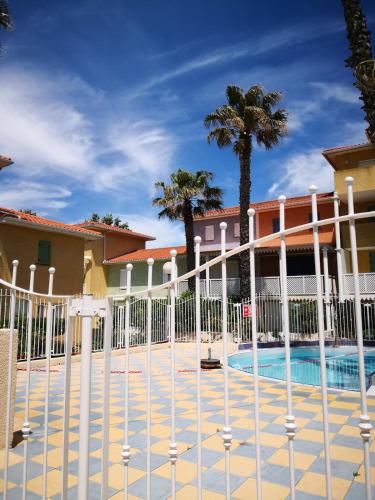 une clôture à côté d'une piscine bordée de palmiers dans l'établissement Villa des Alizés, au Cap d'Agde