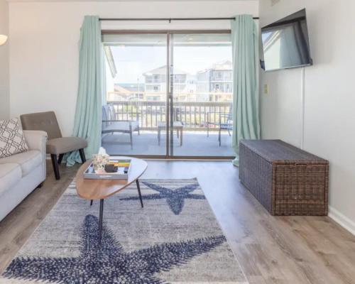 a living room with a couch and a table at Seawind B9- Sea Gem Serenity by Carolina Beach Realty in Carolina Beach
