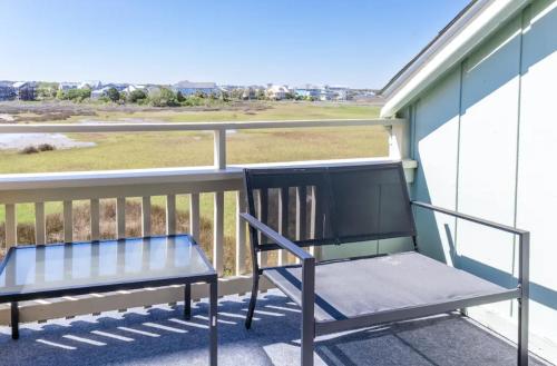 a bench on a balcony with a view of a field at Seawind B9- Sea Gem Serenity by Carolina Beach Realty in Carolina Beach