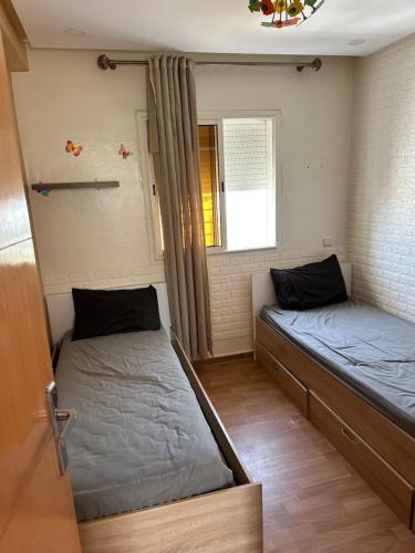 two beds in a room with a window at Ahmed 205 in Temara