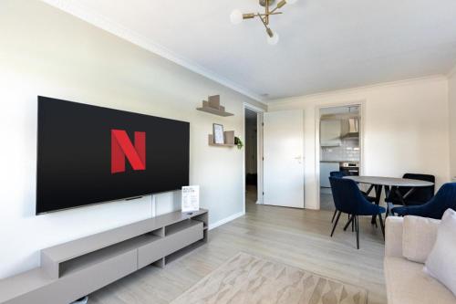 a living room with a tv on a wall at West London Apartment with easy access to Heathrow Airport & Twickenham Rugby Stadium in Hounslow