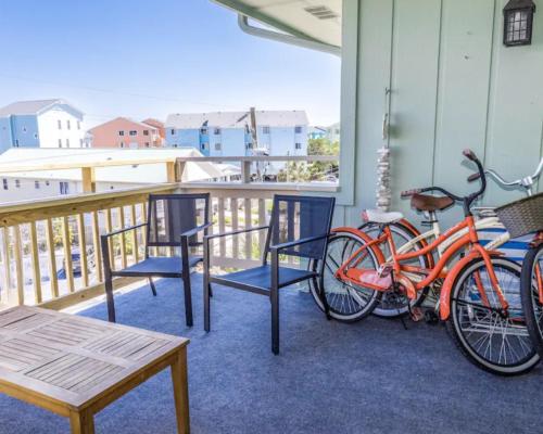 two bikes parked on a porch with a table and chairs at Seawind B9- Sea Gem Serenity by Carolina Beach Realty in Carolina Beach