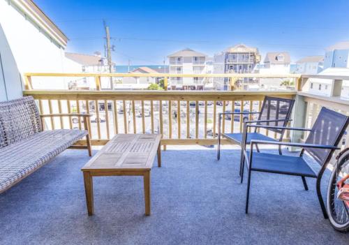 a balcony with a bench and chairs on a balcony at Seawind B9- Sea Gem Serenity by Carolina Beach Realty in Carolina Beach