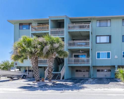 a building with palm trees in front of it at Seawind B9- Sea Gem Serenity by Carolina Beach Realty in Carolina Beach