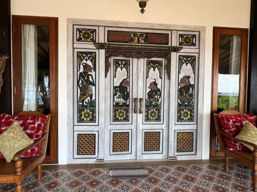 a large wooden door in a room with two chairs at Kampung Kecil Beach Front Boutique Hotel in Kubu