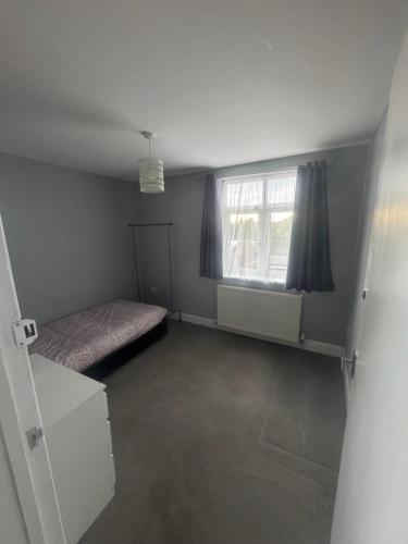 an empty room with a bed and a window at North London Room in Enfield Lock