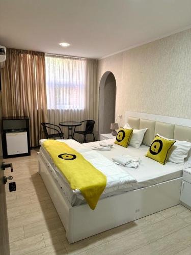 a bedroom with a large white bed with yellow pillows at Aura Plaza Hotel in Tbilisi City