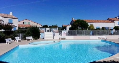 une grande piscine d'eau bleue en face d'une maison dans l'établissement Le Chêne Vert, piscine et forêt, à Saint-Jean-de-Monts
