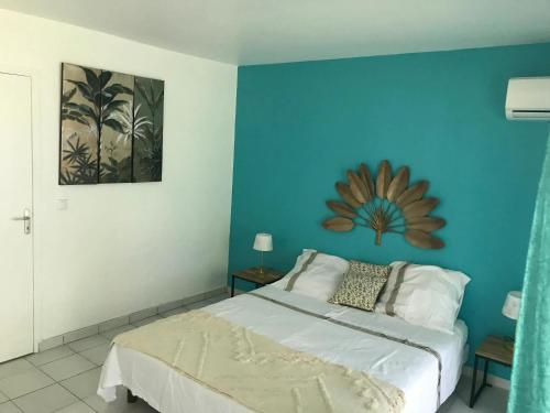Un dormitorio con una cama con una pared azul. en Studio climatisé à Grand-Bourg 20 m² avec piscine, en Grand-Bourg