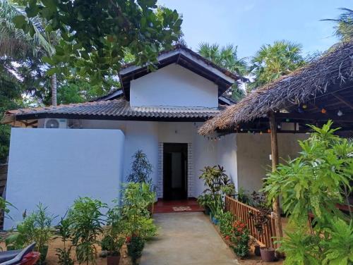a small white house with a thatched roof at Surf Dream Villa Arugambay in Arugam Bay