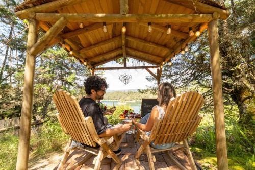 a man and woman sitting in chairs under a pergola at Levit Glamping - Hotel Guatapé Peñol in Guatapé
