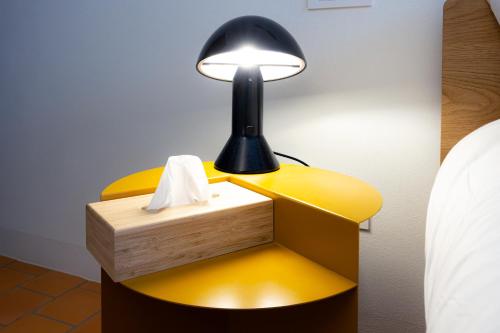a lamp on a yellow table next to a bed at Lunavi in Forte dei Marmi