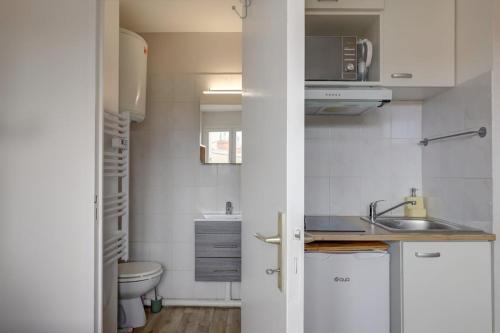Il comprend une petite cuisine blanche avec un lavabo et des toilettes. dans l'établissement Studio cosy calme de 14 m2 - Plein centre, à Toulouse
