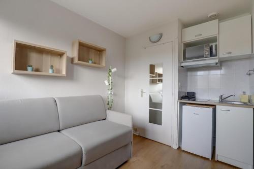 un salon avec un canapé blanc et une cuisine dans l'établissement Studio cosy calme de 14 m2 - Plein centre, à Toulouse