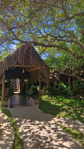 a house with a thatched roof in a yard at Mapu in Pipa