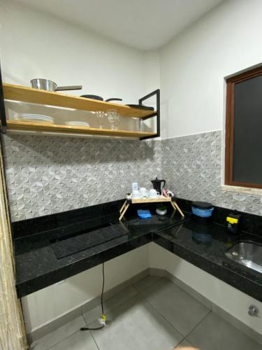 a kitchen with a black counter top and a sink at Pousada Solare Home in São Miguel do Gostoso