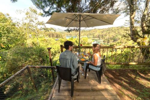 a man and woman sitting at a table under an umbrella at Levit Glamping - Hotel Guatapé Peñol in Guatapé
