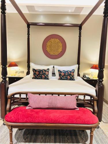 a bedroom with a four poster bed with a red bench at Fountain, Mahabaleshwar - IHCL SeleQtions in Mahabaleshwar