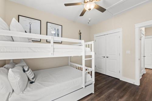 a bedroom with white bunk beds and a ceiling fan at Beach House - Simple Pleasures by Panhandle Getaways in Port Saint Joe