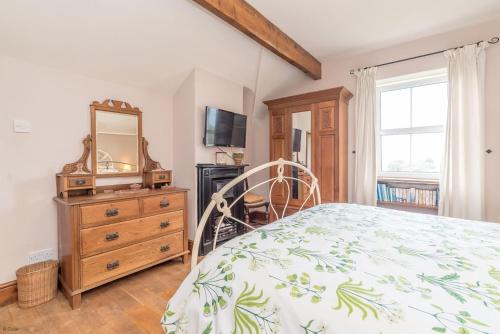 a bedroom with a bed and a dresser and a mirror at Perthi-Uchaf in Cwm-y-glo