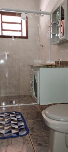 a bathroom with a toilet and a glass shower at Chácara do vô Meireles in Serra Negra